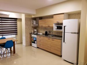 a kitchen with a white refrigerator and a table at Malvinas Departamentos in San Rafael