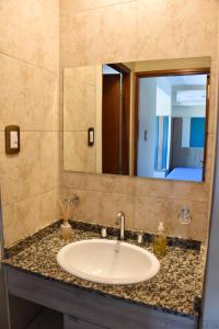 Un lavabo de baño con un espejo grande encima. en Malvinas Departamentos, en San Rafael 15 fotos más