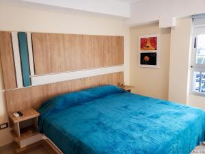 Un dormitorio con una cama azul y una ventana. en Malvinas Departamentos, en San Rafael