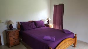 a bedroom with a purple bed with two night stands at Te Vaiora Villa in Rarotonga