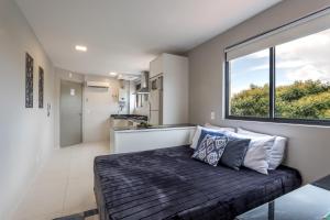 1 dormitorio con cama y ventana grande en Pleione Flats en Curitiba