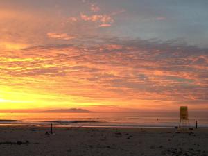 a sunset on a beach with a lifeguard chair at Beach Side Inn Shirahama in Shimoda