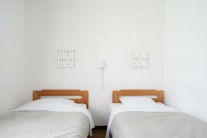 two beds in a room with white walls at Beach Side Inn Shirahama in Shimoda
