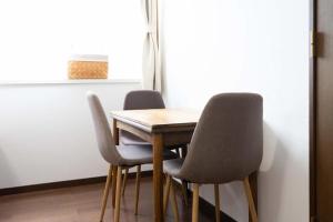 a wooden table with four chairs and a window at Beach Side Inn Shirahama in Shimoda
