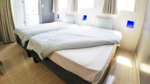 2 camas en una habitación de hotel con sábanas blancas en Across Omoromachi Naha en Naha