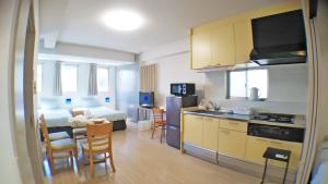 a kitchen and a living room with a table and chairs at Across Omoromachi Naha in Naha