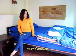 a woman sitting on top of a blue bed at Lungphut Homestay in Chiang Mai