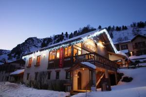 Un bâtiment avec des lumières de Noël dans la neige dans l'établissement Chez Philippe - Appartements et Chalets - Panoramic Village vue Glaciers, à La Grave