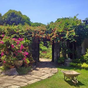 a garden with flowers and a stone arch with a bench at Dormitels.ph Ermita in Manila
