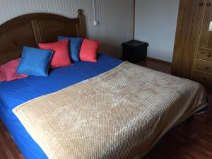 a bed with red and blue pillows on it at Cabaña Centro Pitrufquen in Pitrufquén