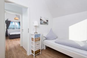 a white bedroom with a bed and a mirror at Maine in Olpenitz