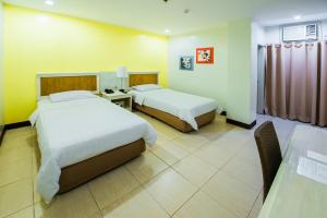 una habitación de hotel con dos camas y una mesa en L'Fisher Ecotel, en Bacolod