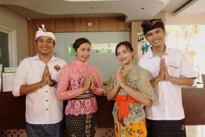 a group of four people praying in a kitchen at Choice Stay Hotel Denpasar in Denpasar