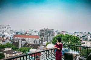 Eine Frau steht auf einem Balkon mit Blick auf eine Stadt in der Unterkunft The Chi Boutique Hotel in Hanoi