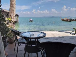 een tafel en stoelen op een patio met water bij Seaside home in Ko Mook