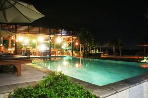 a swimming pool at night with a table and an umbrella at Pemedal Beach Resort in Nusa Lembongan