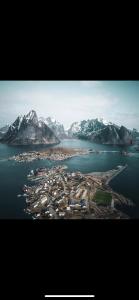 an island in the water with snow covered mountains at Reinebringen Apartments in Reine