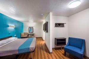 a bedroom with a bed and a blue chair at Motel 6-Irving, TX - Irving DFW Airport East in Irving