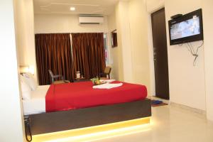 a hotel room with a red bed and a flat screen tv at Choice Classic Hotel in Pune