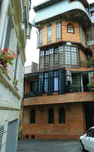 a large brick building with a balcony and a car at Babilina B&B in Tbilisi City