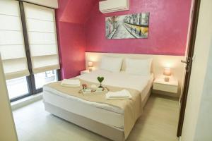 een slaapkamer met een wit bed en een roze muur bij Noris Apart with Garage in Plovdiv