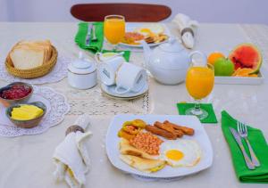 a table with a plate of breakfast foods and orange juice at The Berrycove Bungalow in Kurunegala