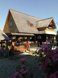 una casa con un banco y flores en el patio en Complex Traditional Căsuța Bunicilor-Breb en Breb