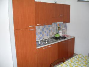 a small kitchen with wooden cabinets and a sink at Affittacamere Peonia in Oliena