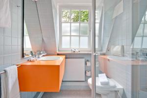 La salle de bains est pourvue d'un lavabo orange et de toilettes. dans l'établissement Das Gästehaus der Elb Lounge "Self Check In", à Hambourg