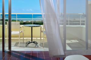 einen Balkon mit einem Tisch und Stühlen sowie Meerblick in der Unterkunft OKINAWA KARIYUSHI RESORT EXES Ishigaki in Ishigaki-jima