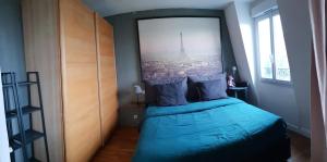 una camera da letto con un letto e una grande finestra di Grand appartement ouvert type loft avec vue dégagée proche La Défense & U Arena a La Garenne-Colombes