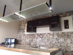 a kitchen with black cabinets and a stone wall at Seaview Mansion Dalaguete Apartment 4 -Family in Dalaguete