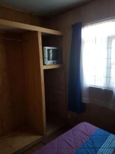 a bedroom with a bed and a tv on a shelf at Cabañas Patricia Licanray in Licán Ray