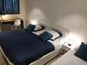 a bedroom with two beds with blue pillows and a desk at Le séquoia in Saint-Sébastien-sur-Loire