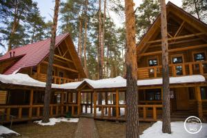 Una cabaña de madera en el bosque con nieve. en BKC Country, en Sosnoviy Bor