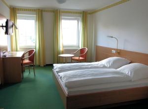 een slaapkamer met een bed en 2 stoelen en een bureau bij Landgasthof Meisel in Kalchreuth