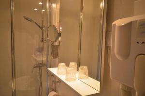 un bagno con doccia, lavandino e specchio di Hôtel Vauban a Belfort