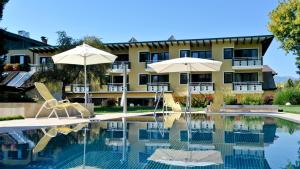 un hotel con una piscina con sillas y sombrillas en Familiengut Ertlhof en Seeboden