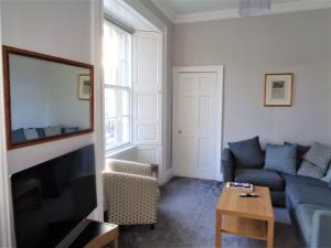 salon z kanapą i telewizorem w obiekcie Heritage City - Central York Place Apt w Edynburgu