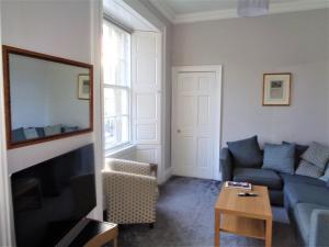 a living room with a couch and a tv at Heritage City - Central York Place Apt in Edinburgh