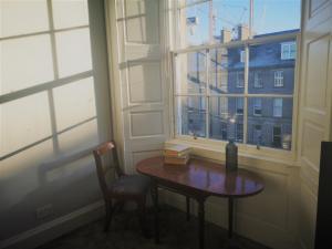 stół i krzesło w pokoju z oknem w obiekcie Heritage City - Central York Place Apt w Edynburgu