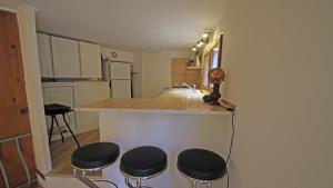 une cuisine avec quatre tabourets à un comptoir de cuisine dans l'établissement Le Bateau, à Sainte-Maxime