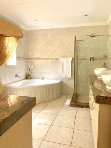 a bathroom with a tub and a sink and a shower at La Barune Guest House in Tzaneen