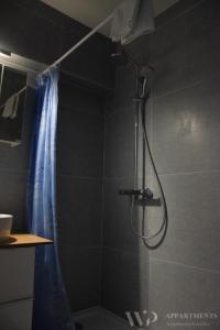 La salle de bains est pourvue d'une douche et d'un rideau de douche bleu. dans l'établissement Residentie Caraibes, 9de verdieping, à Blankenberge