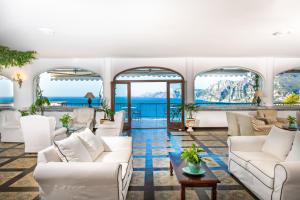a living room with white furniture and a view of the ocean at Grand Hotel Tritone in Praiano