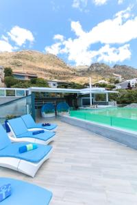 a swimming pool with lounge chairs on the roof of a resort at GORDON's SHORE LUXURY APARTMENTS - Solar Powered in Gordonʼs Bay