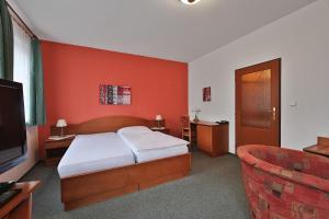 a bedroom with a bed and a tv and a couch at Attic Hotel in Prague