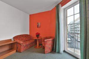 a living room with a red chair and a window at Attic Hotel in Prague