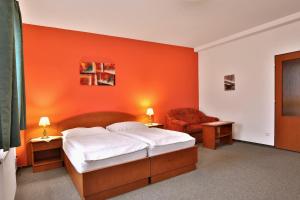 a bedroom with an orange wall with a bed and a chair at Attic Hotel in Prague
