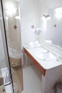 a white bathroom with a sink and a shower at Hotel Bellis in Lublin